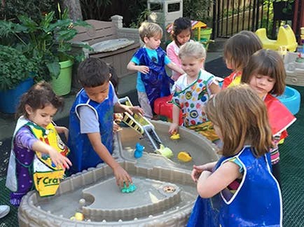 Children playing with water and toys in a water table