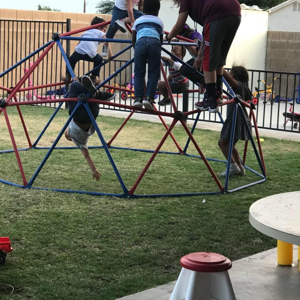 Children playing on a red and blue geometric dome climber