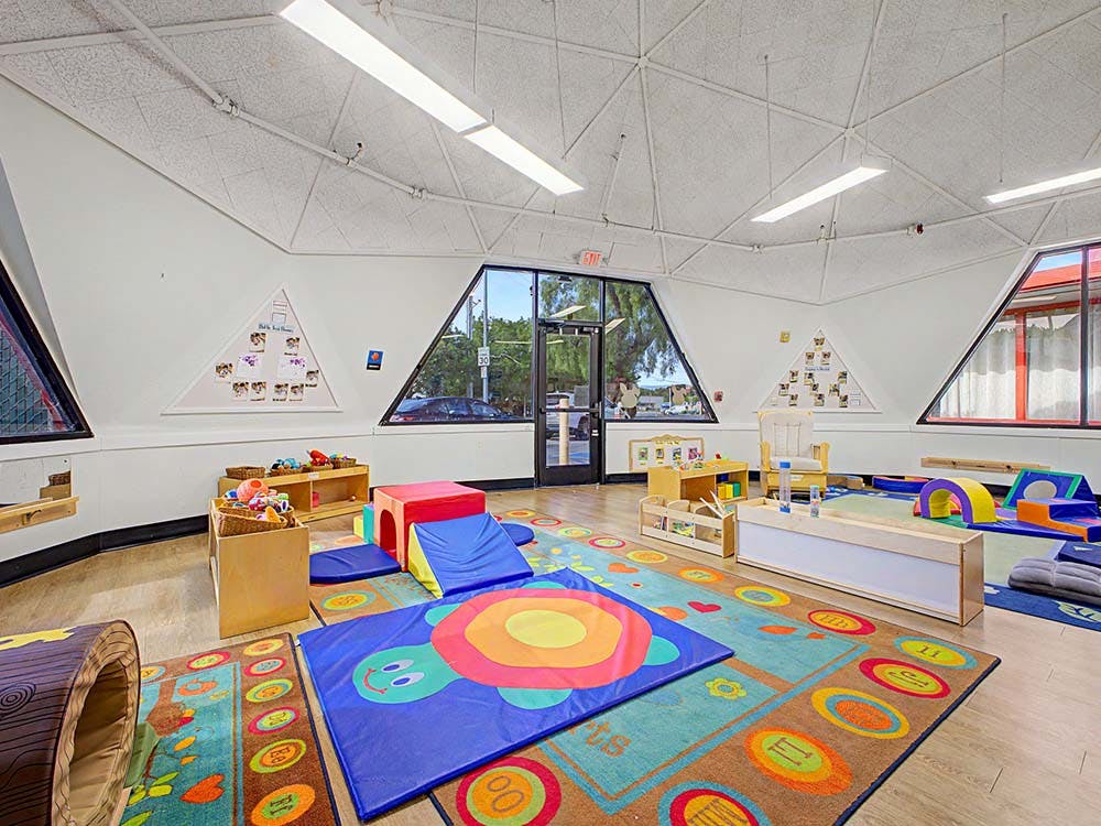 Colorful playroom with soft mats, play structures, and large windows
