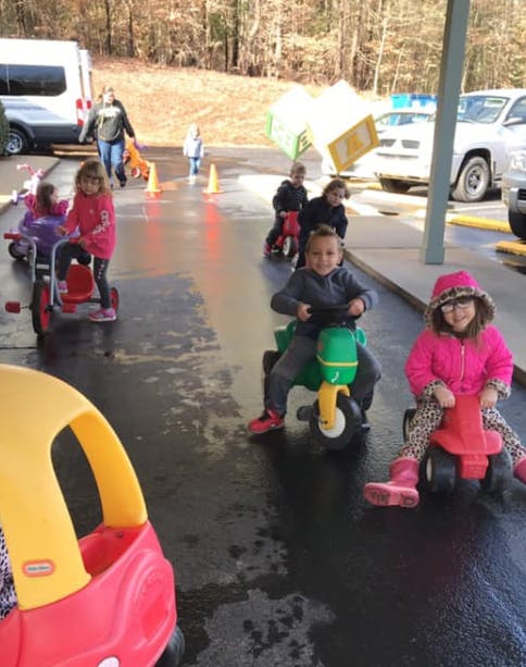 Children riding tricycles and toy cars outdoors