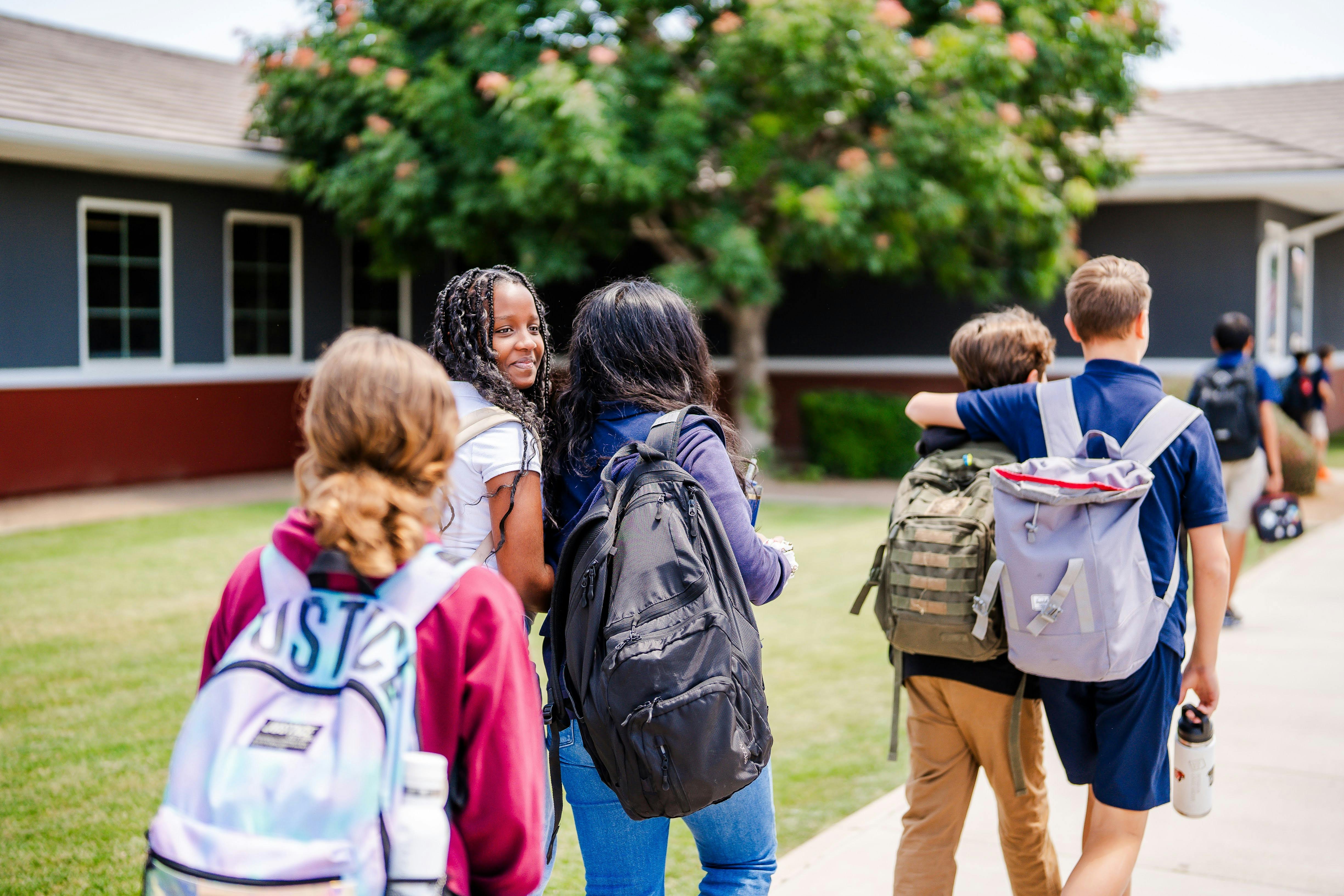 Group of teens and children with backpacks walking outdoors