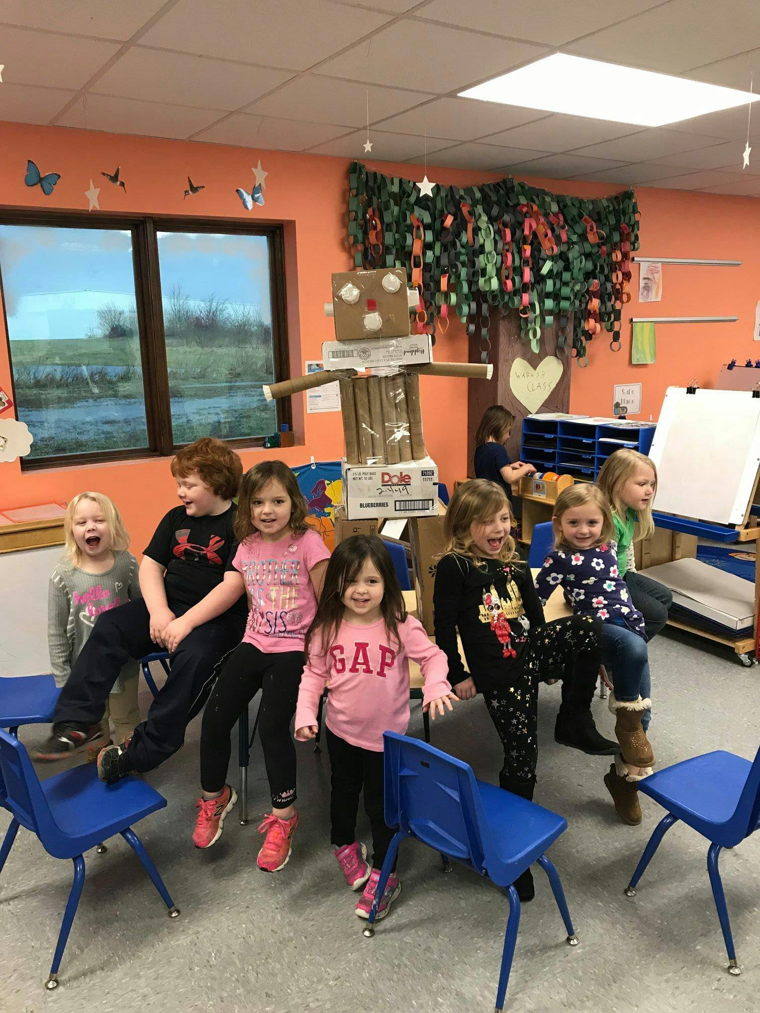 Group of children in a classroom with a cardboard robot