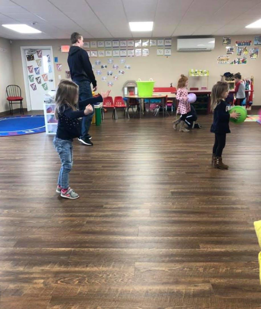 Adult and children in a room with wooden floors