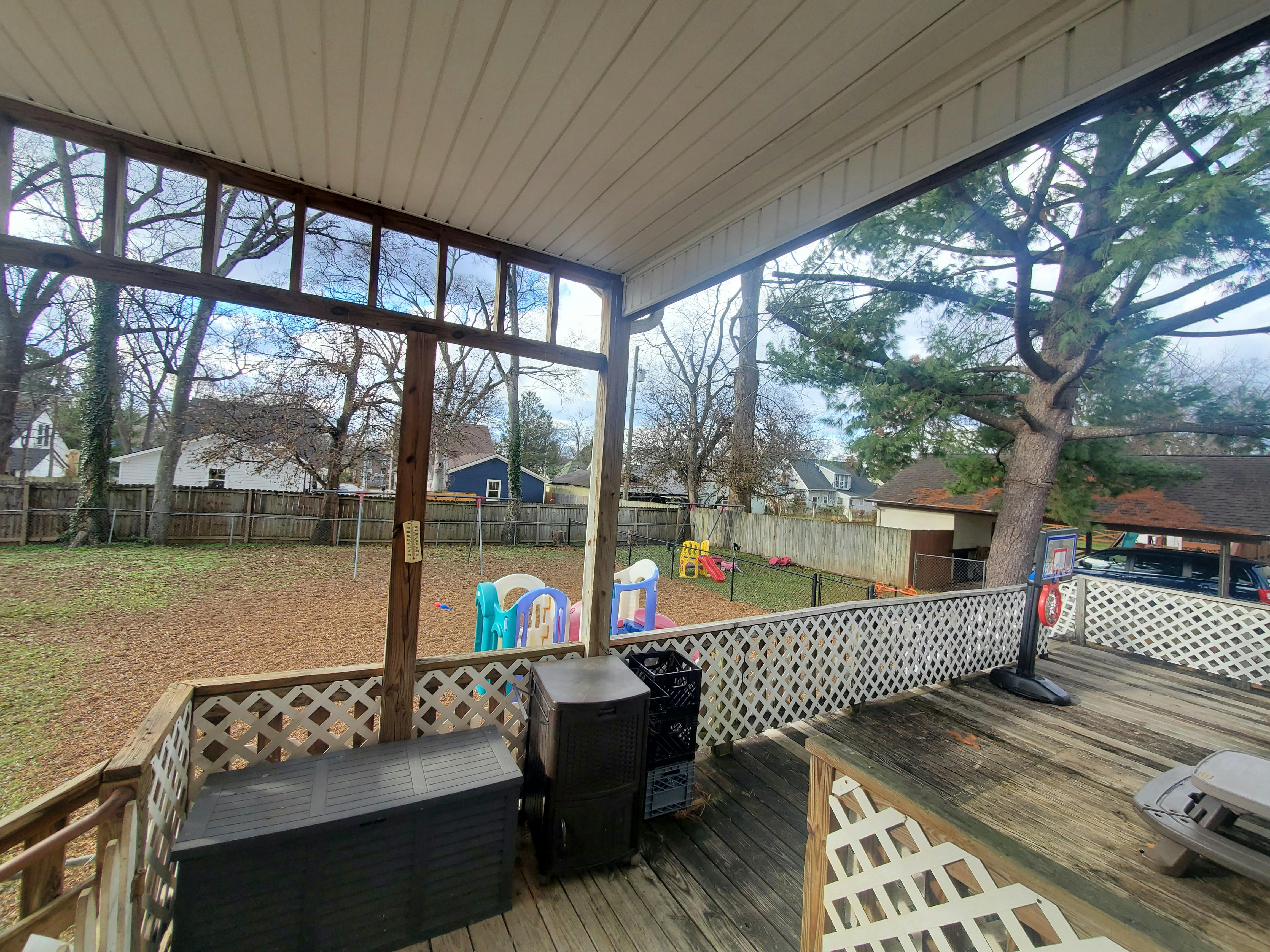 View from a screened-in porch overlooking a backyard with play equipment