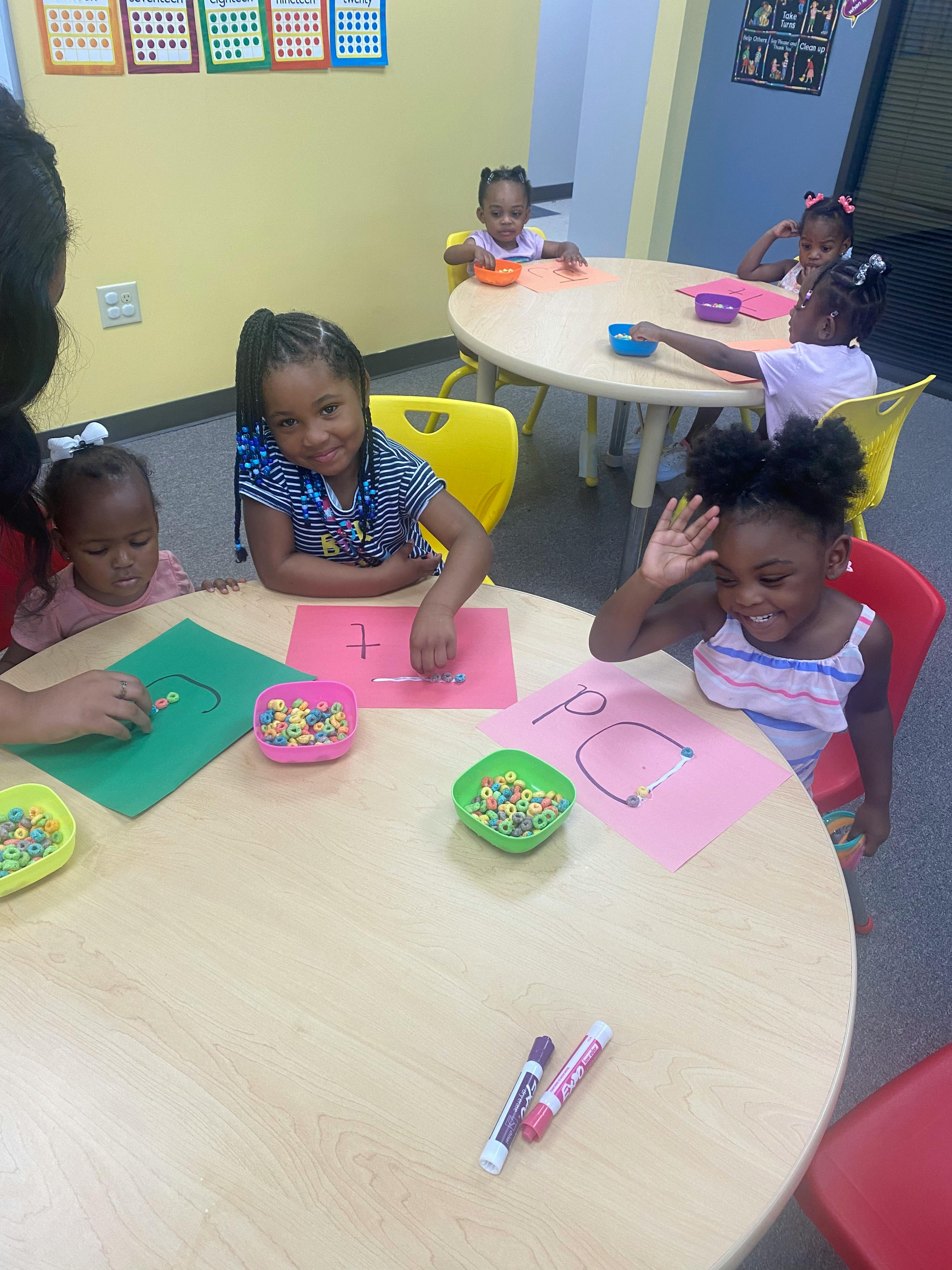 Children at tables in a classroom, some working with craft materials