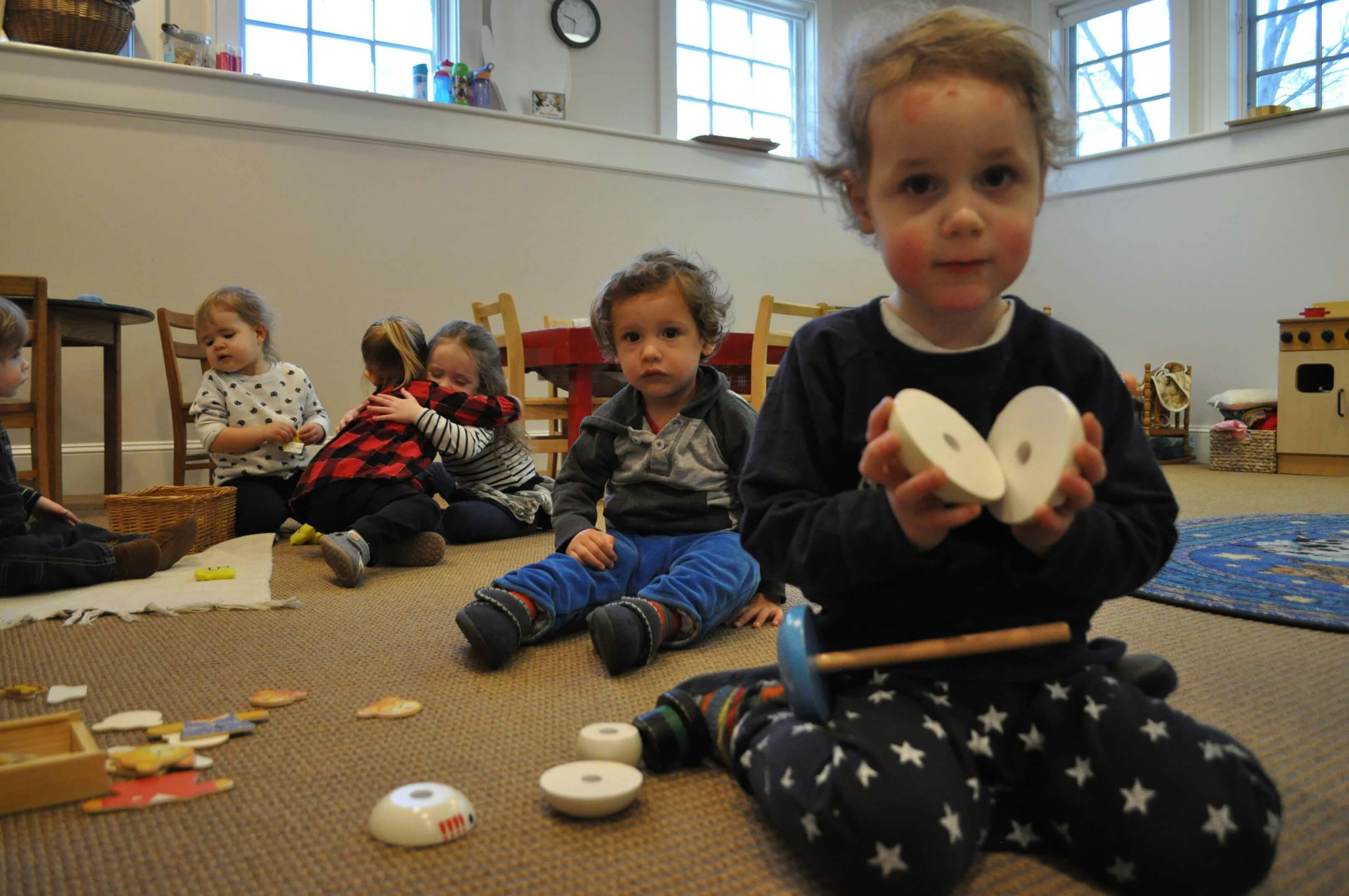 Child holding two white circular objects, other children in background