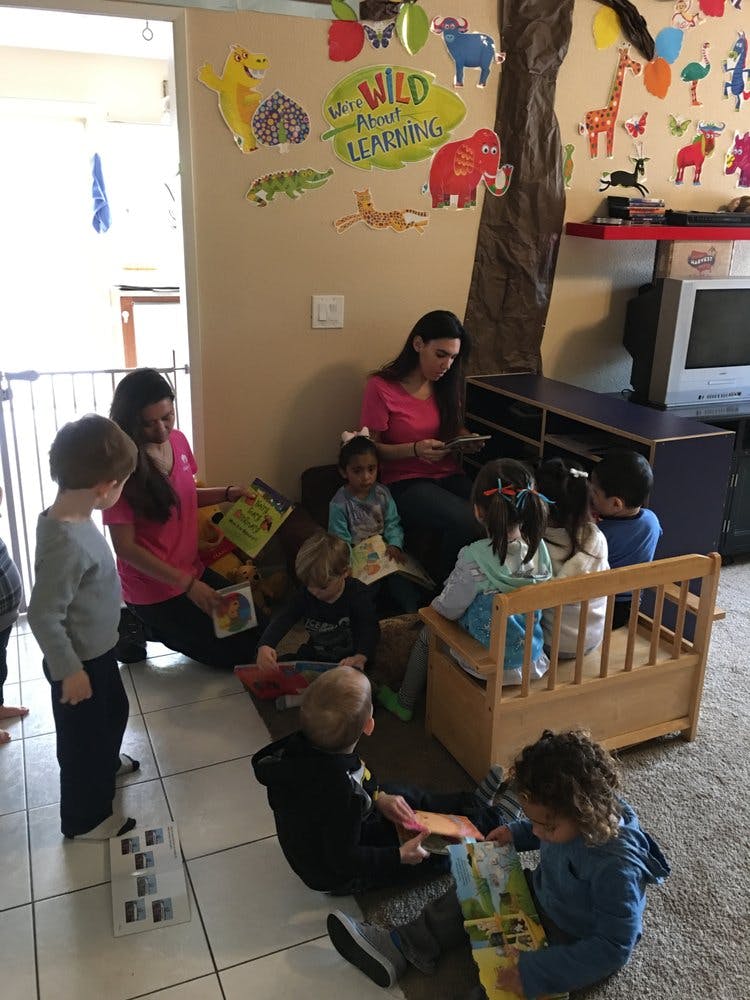 Two people reading to a group of children in a classroom