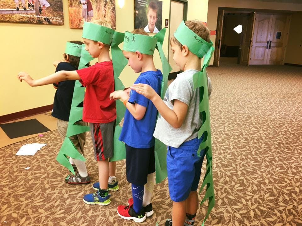 Children in green paper costumes with headbands and tails