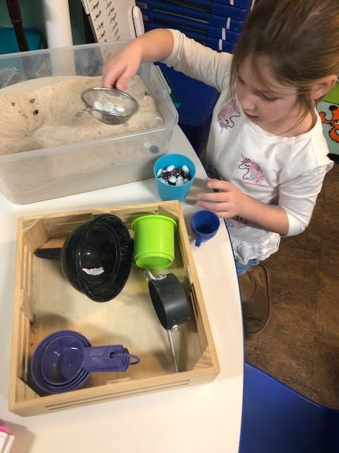 Child playing with sand and kitchen utensils