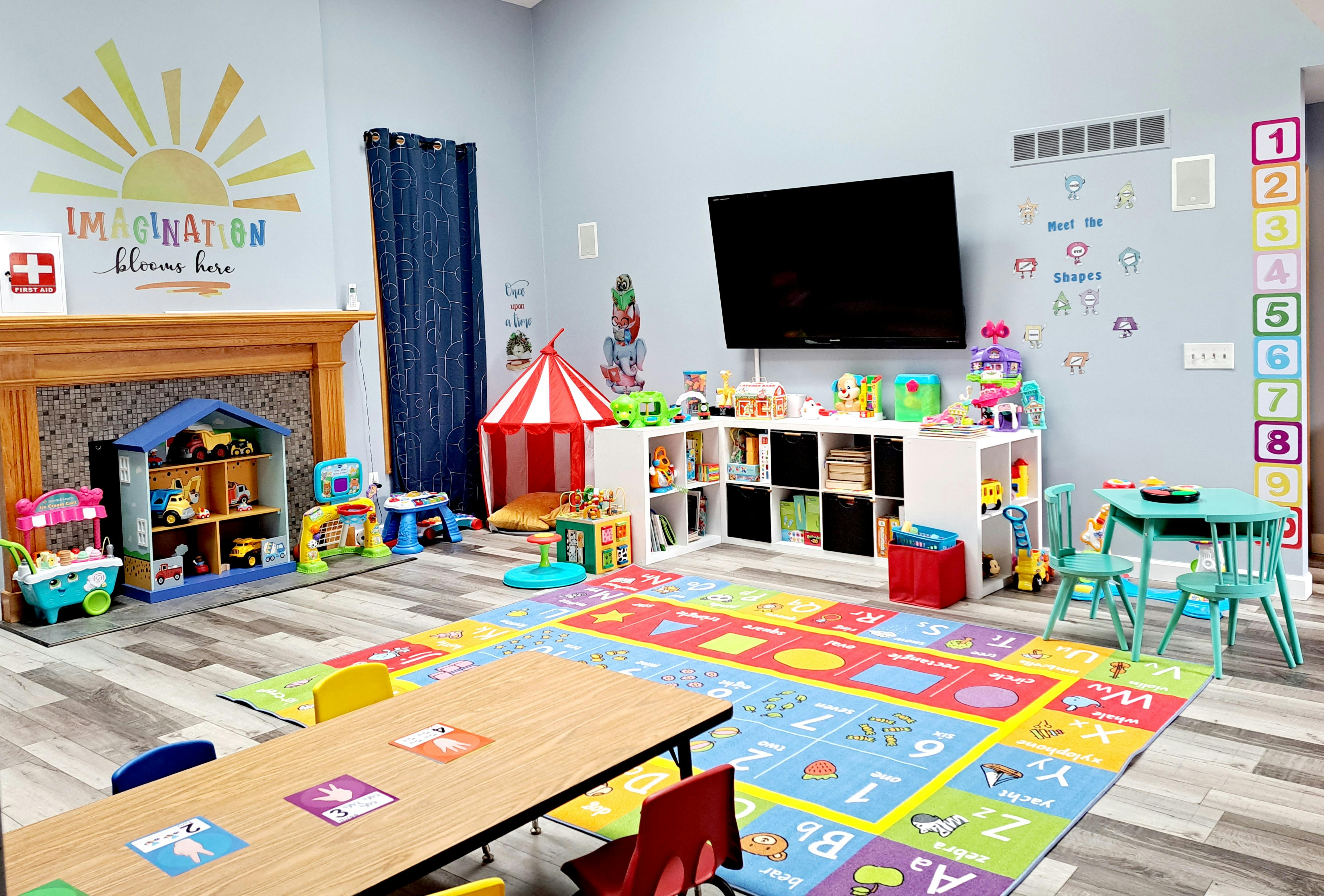 Playroom with colorful alphabet rug, toys, and small tables