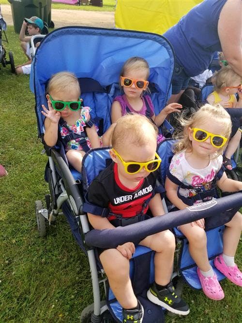 Four children wearing sunglasses in a blue stroller
