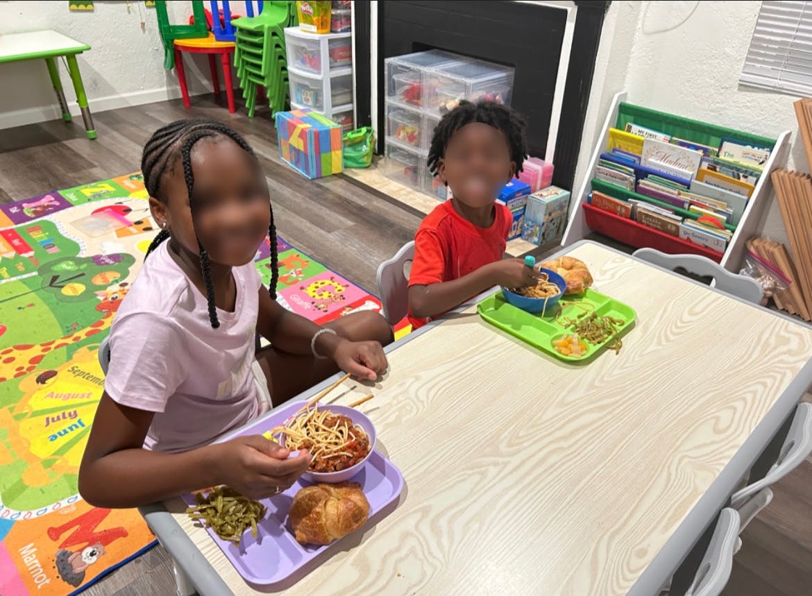 Two children eating at a table in a classroom