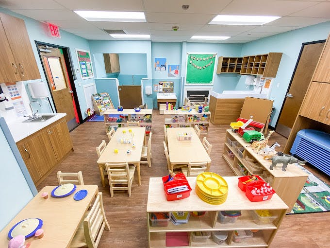 An empty classroom with small tables, chairs, and learning materials