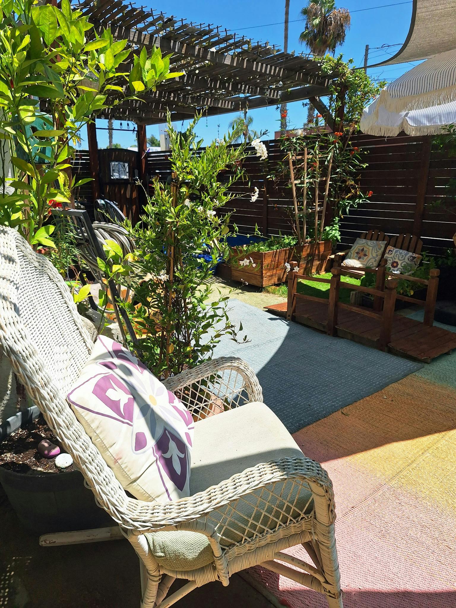 White wicker chair on a patio with a garden pergola and wooden accents