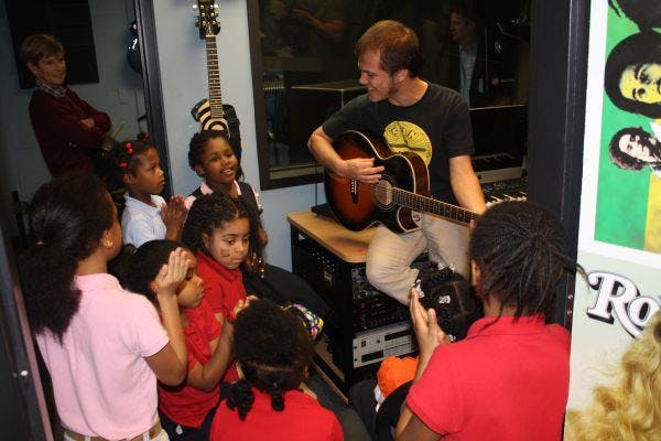 Person playing guitar for a group of children