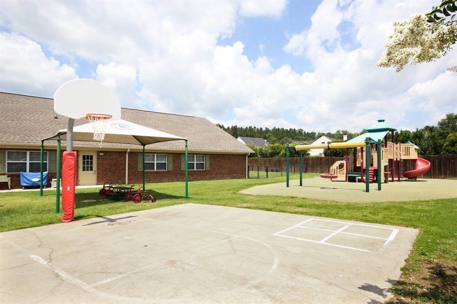 Outdoor basketball court and playground with a building in the background