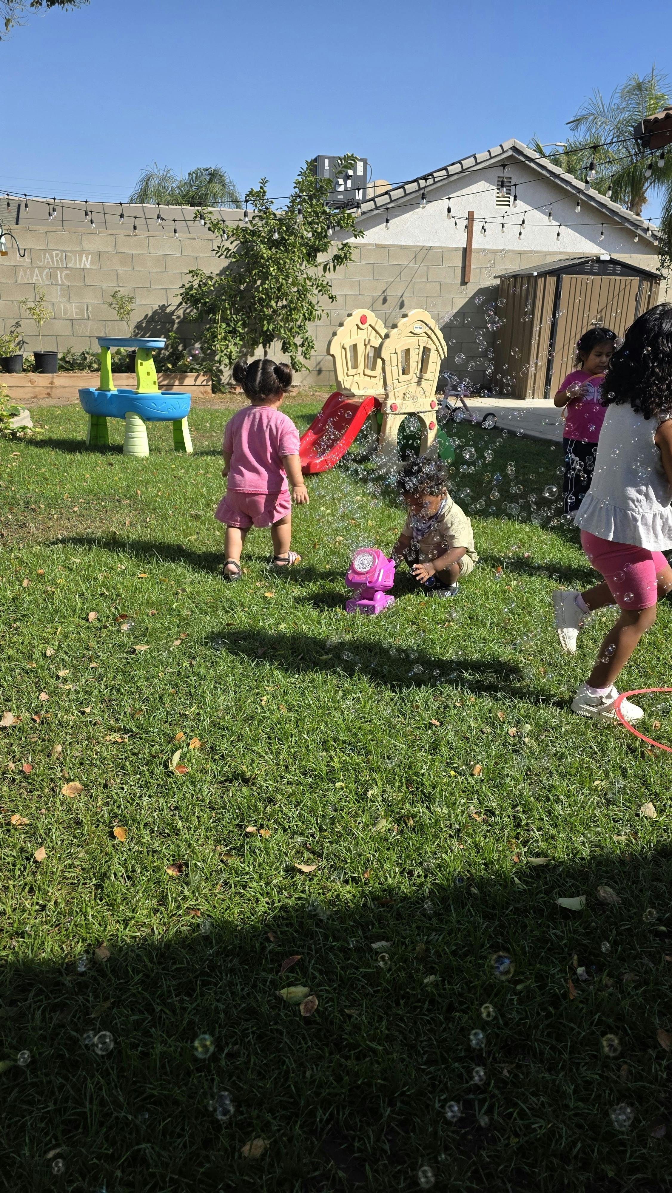 Children playing with bubbles in a grassy backyard