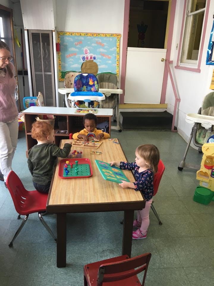 Adult and three children at a table in a classroom