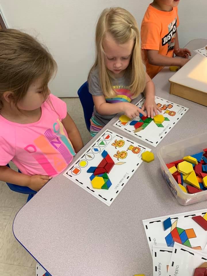 Child playing with colorful geometric shapes on a pattern card