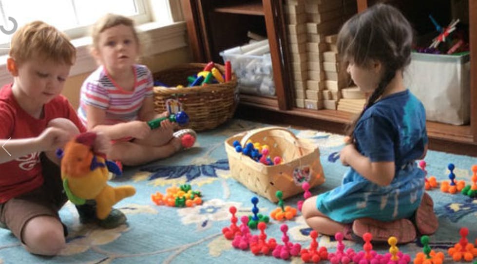 Three children playing with toys on a rug