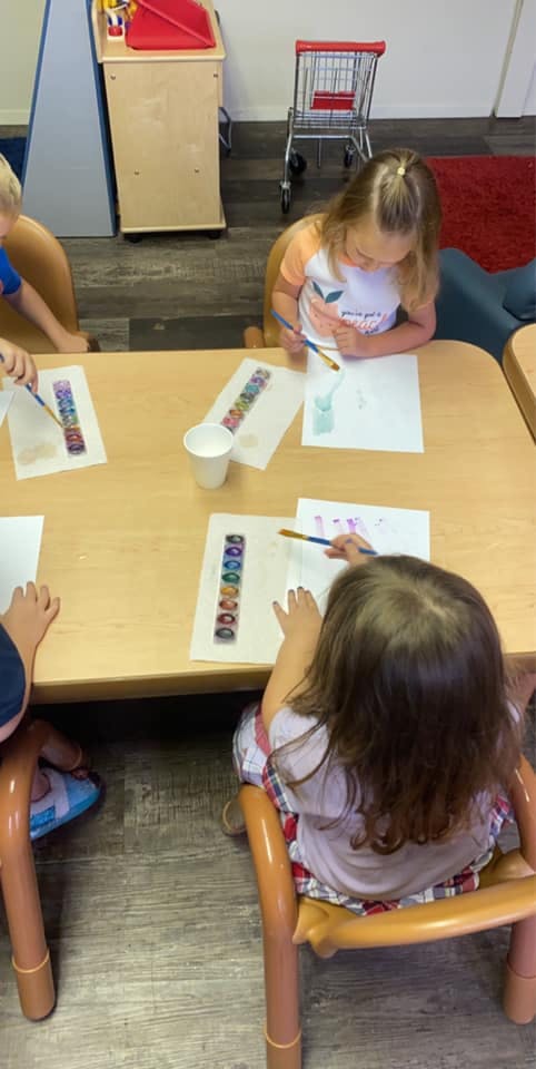 Children painting at a table in a classroom