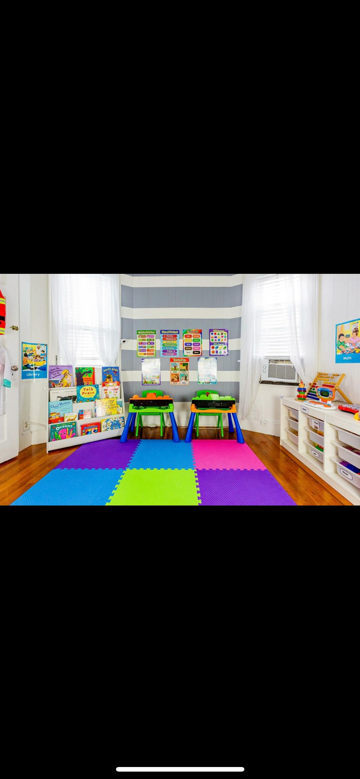Classroom with colorful floor mats, small tables, and a bookshelf