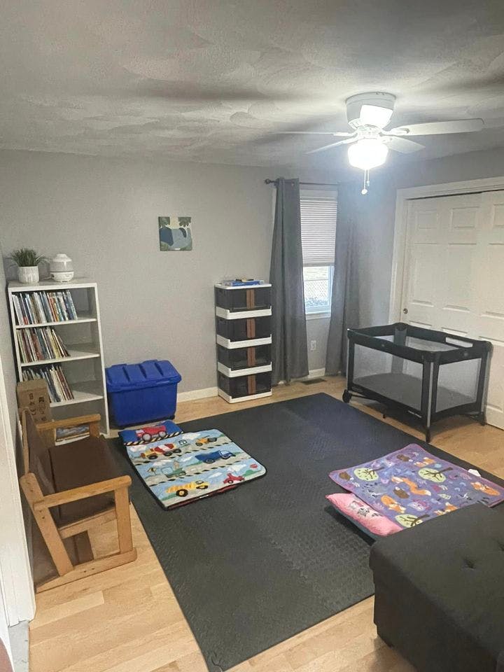 Child's room with a playpen, bookshelf, and play mats on the floor