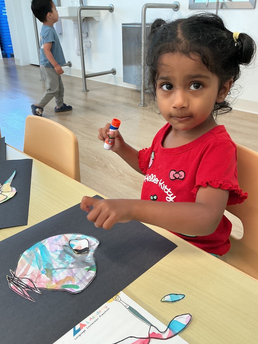 Child gluing a paper craft at a table