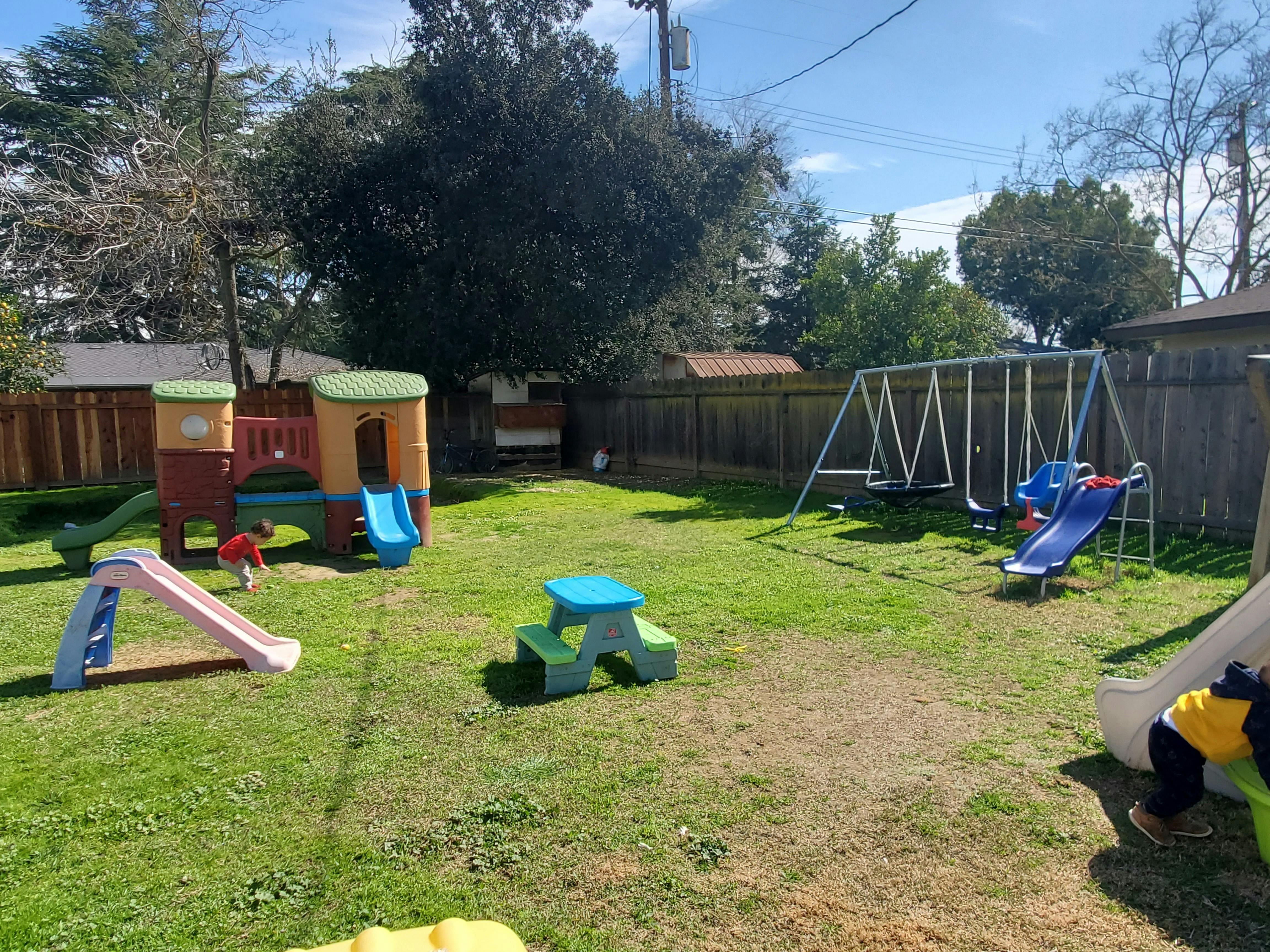 Playground with swings, slides, and play structures in a grassy yard
