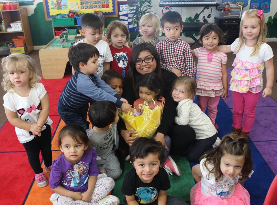 Adult and multiple children gathered around a yellow basket