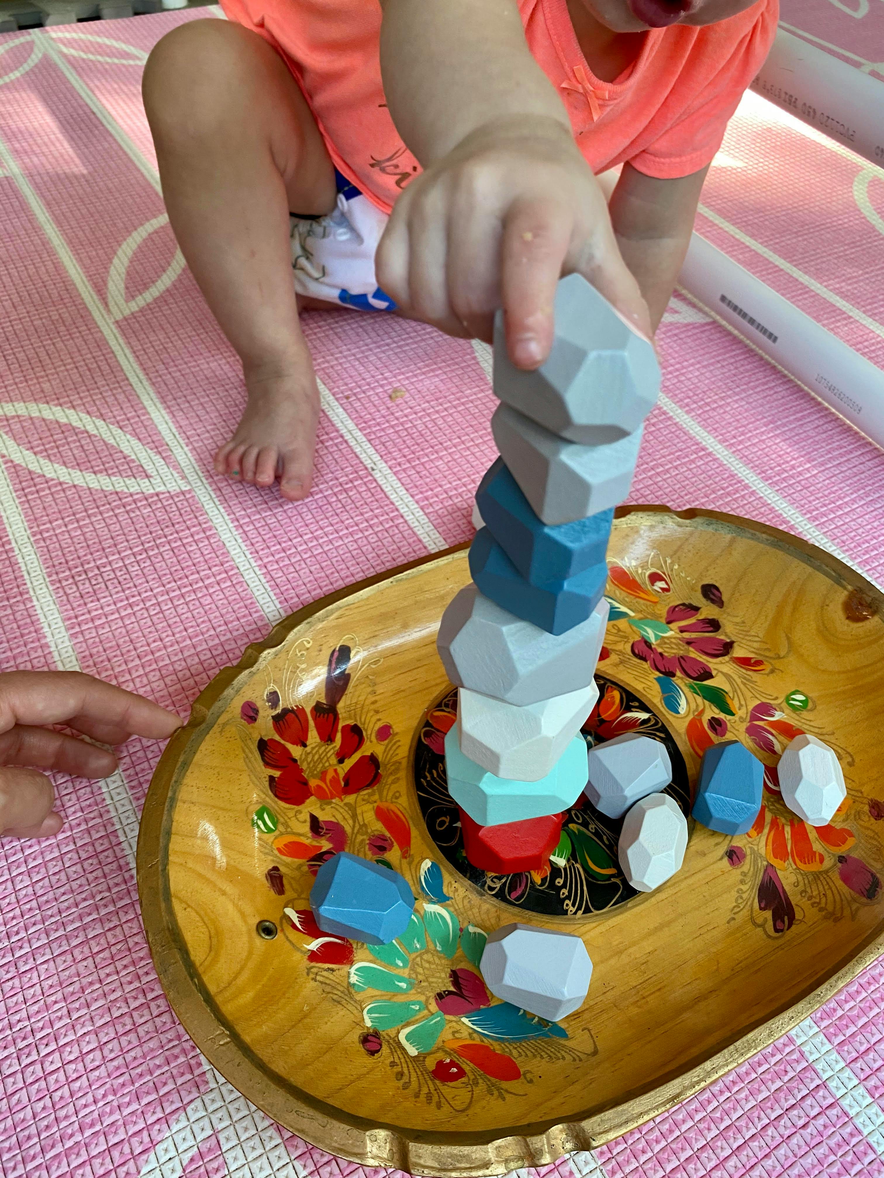 Child stacking colorful geometric blocks on a decorative tray