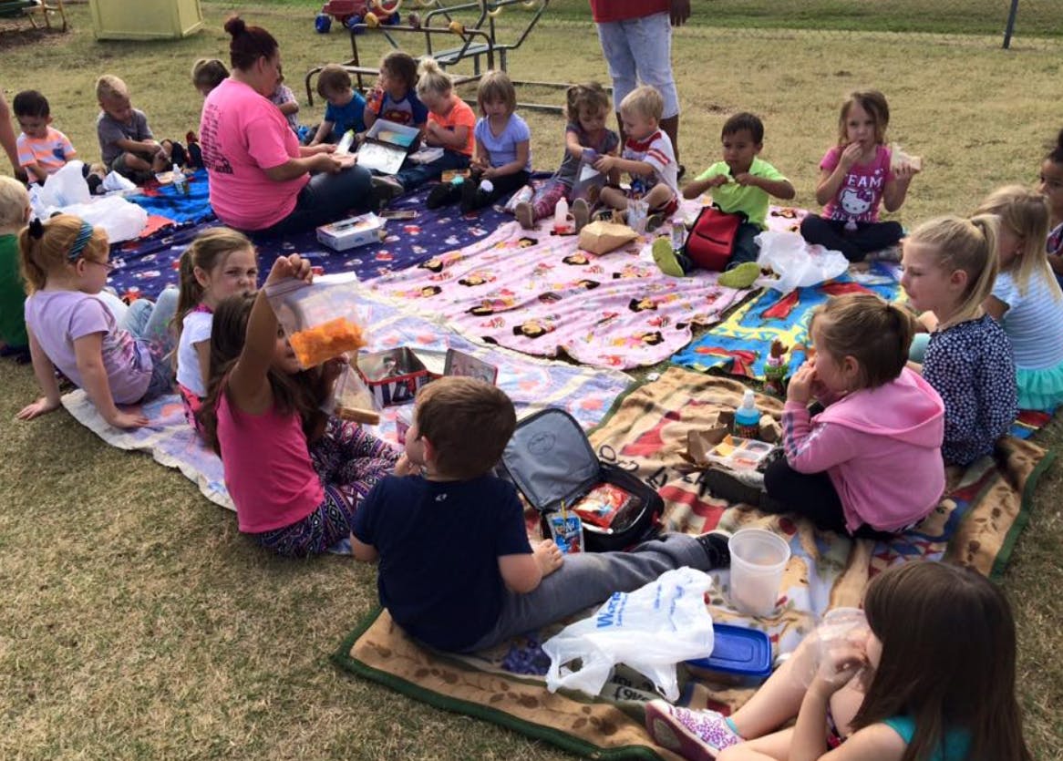 Adult and children sitting on blankets on grass