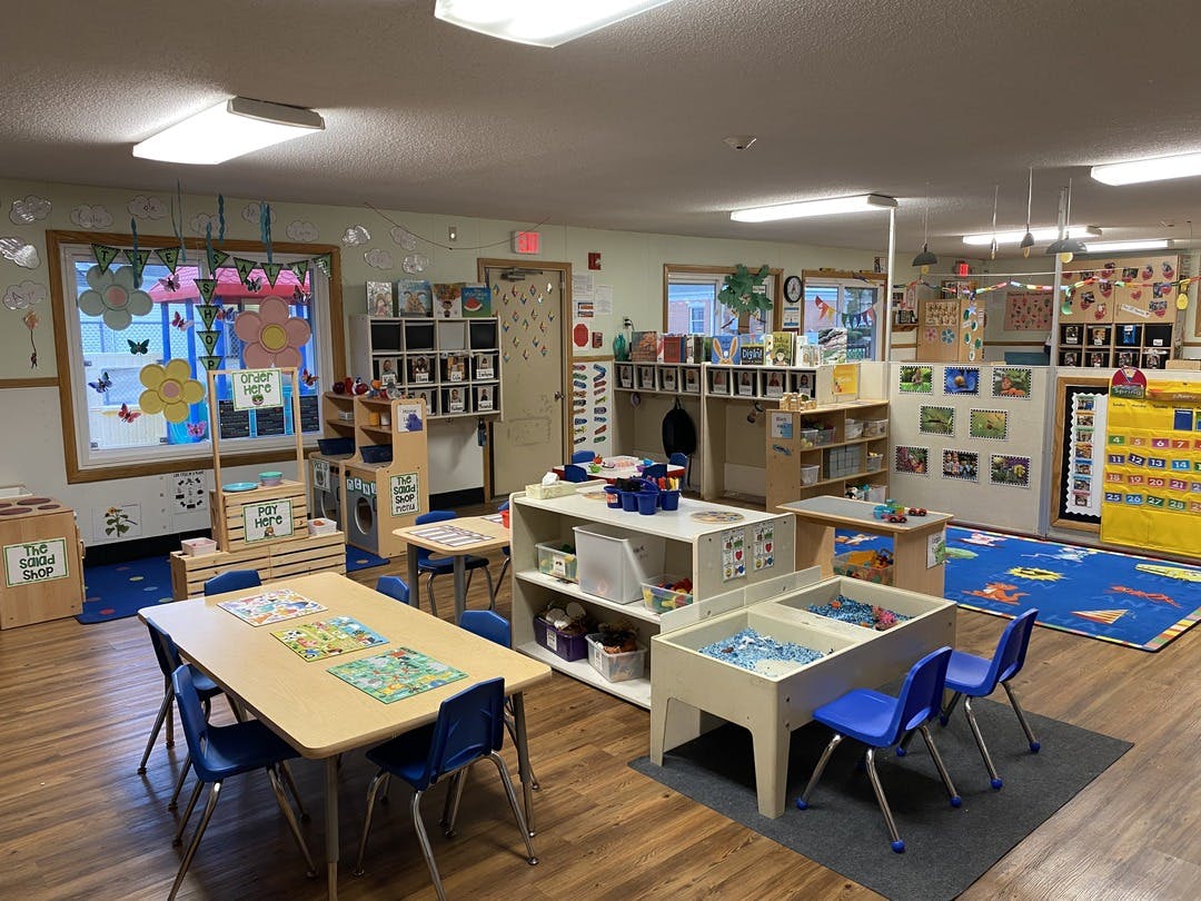 A colorful classroom with tables, chairs, and play areas
