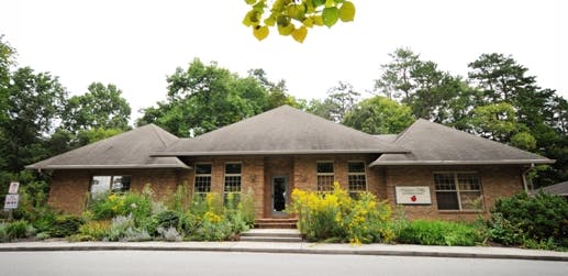 Brick building with a dark roof and landscaping in front of it, a garden