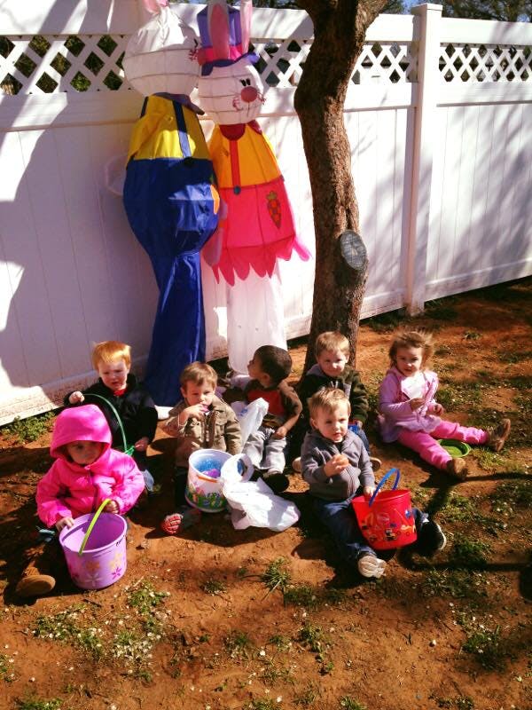 Children sitting on the ground with buckets near large bunny decorations