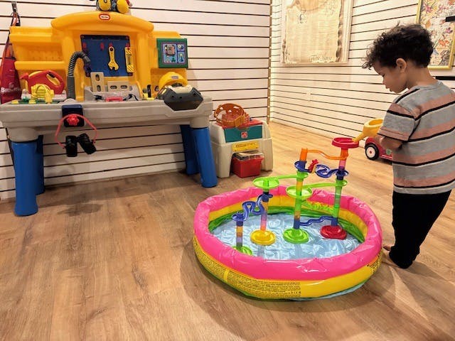 Child playing with a water toy in a small inflatable pool