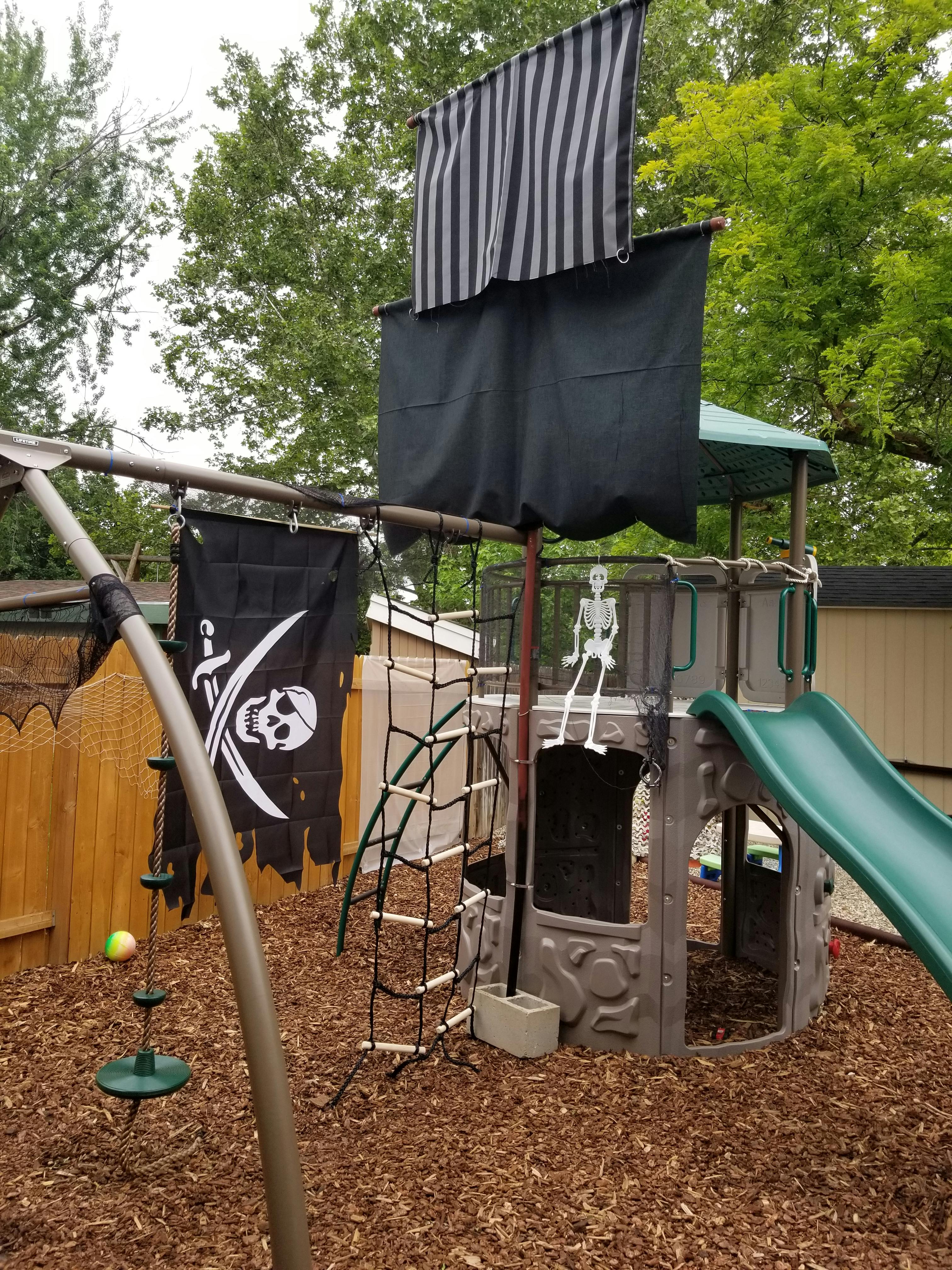 Pirate-themed playground with a slide, climbing net, and skull and crossbones flag