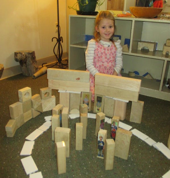Child standing behind a structure made of wooden blocks
