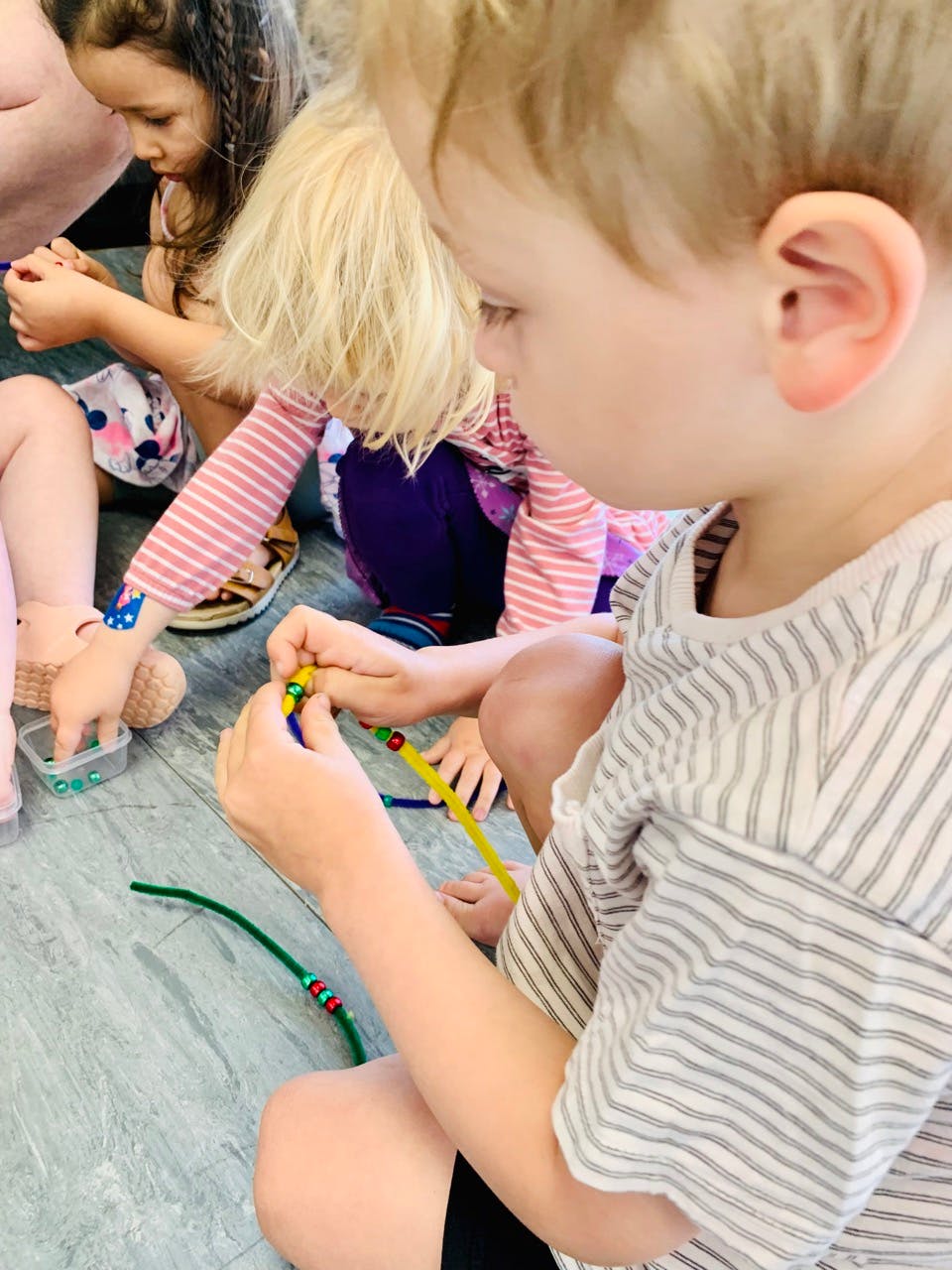 Children making crafts with pipe cleaners and beads