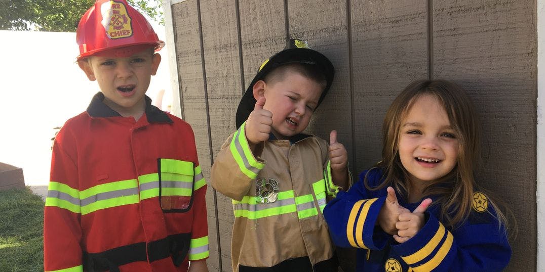 Three children in costumes, two giving thumbs up