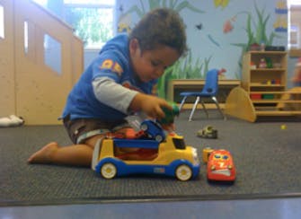 Child playing with toy truck and cars on the floor