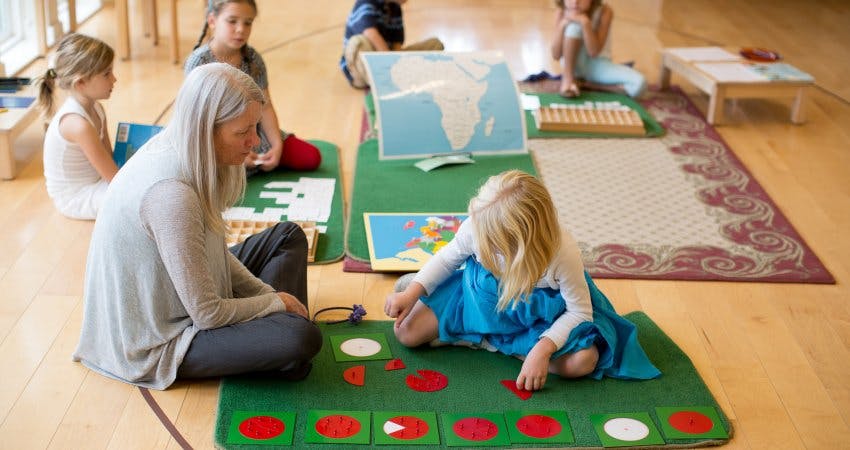Adult and child playing with learning materials on a mat