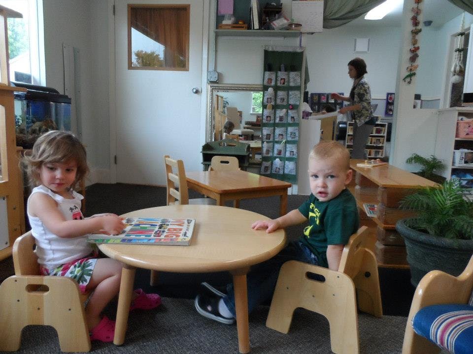Two children sitting at a small table in a room