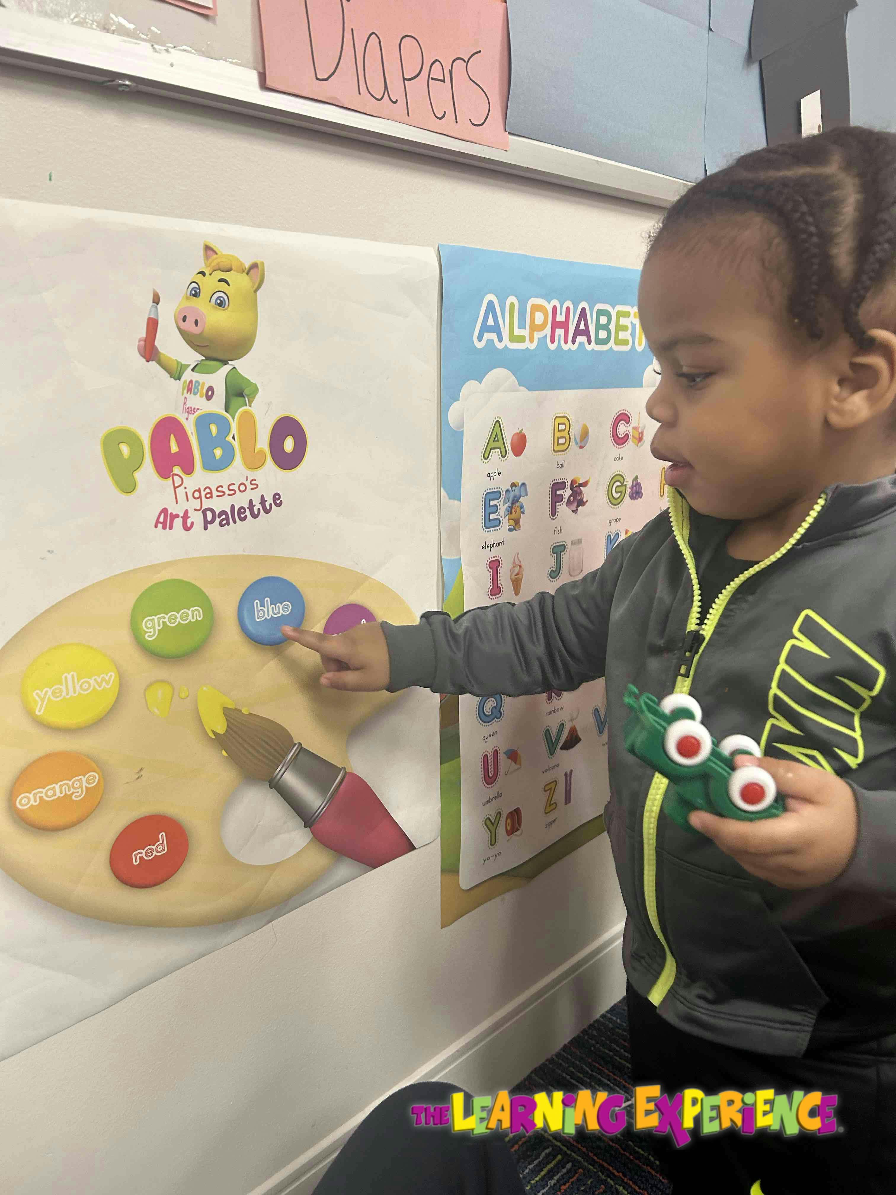 Child pointing at a color on an art palette poster