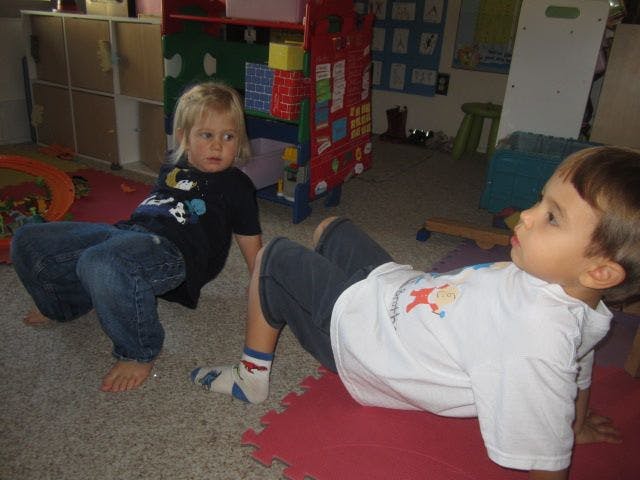Two children on the floor, one sitting up and one lying down