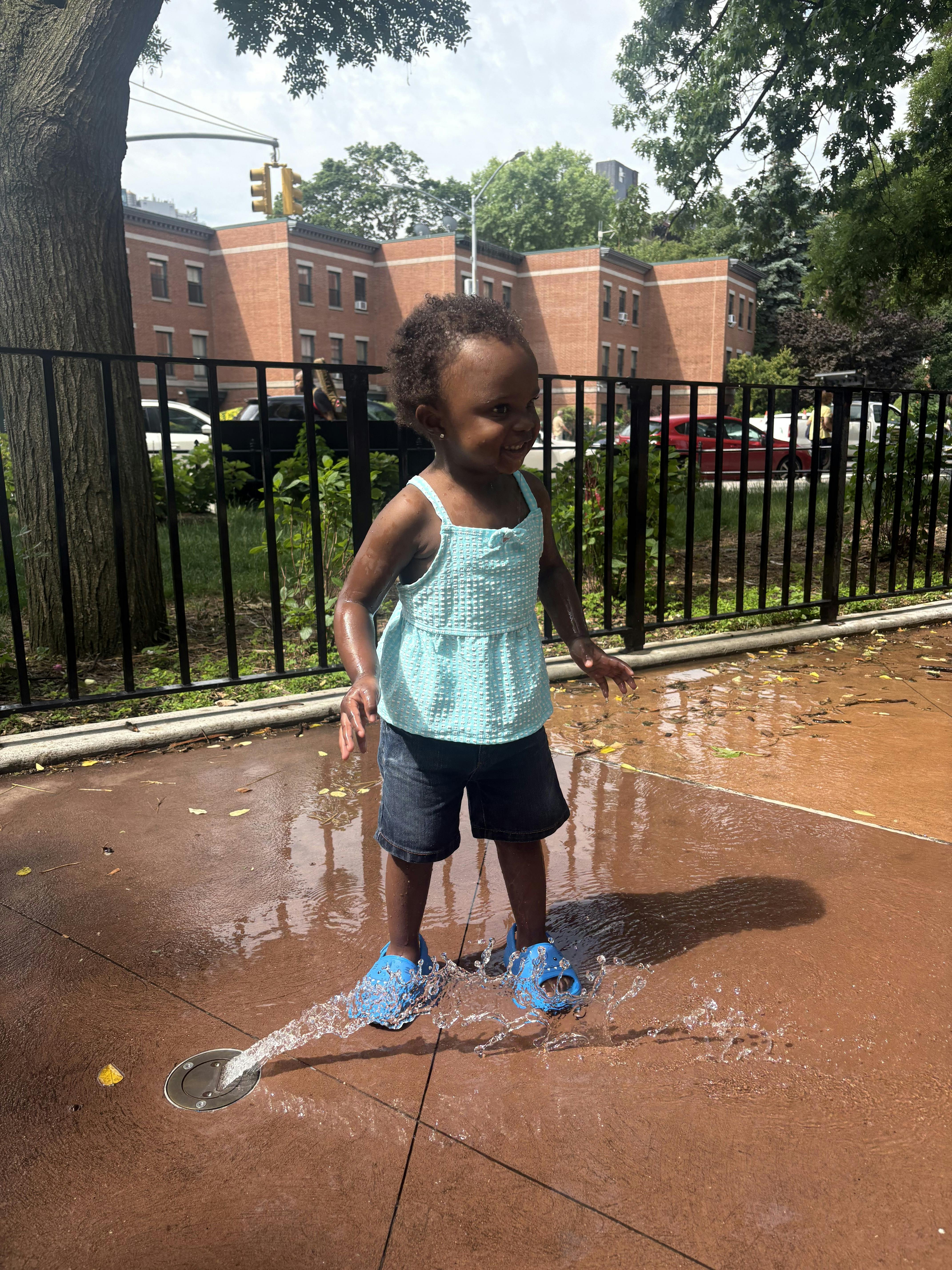 Child playing in a water fountain at a park