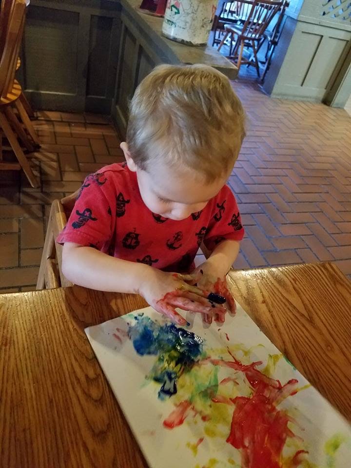 Child finger painting on a white surface