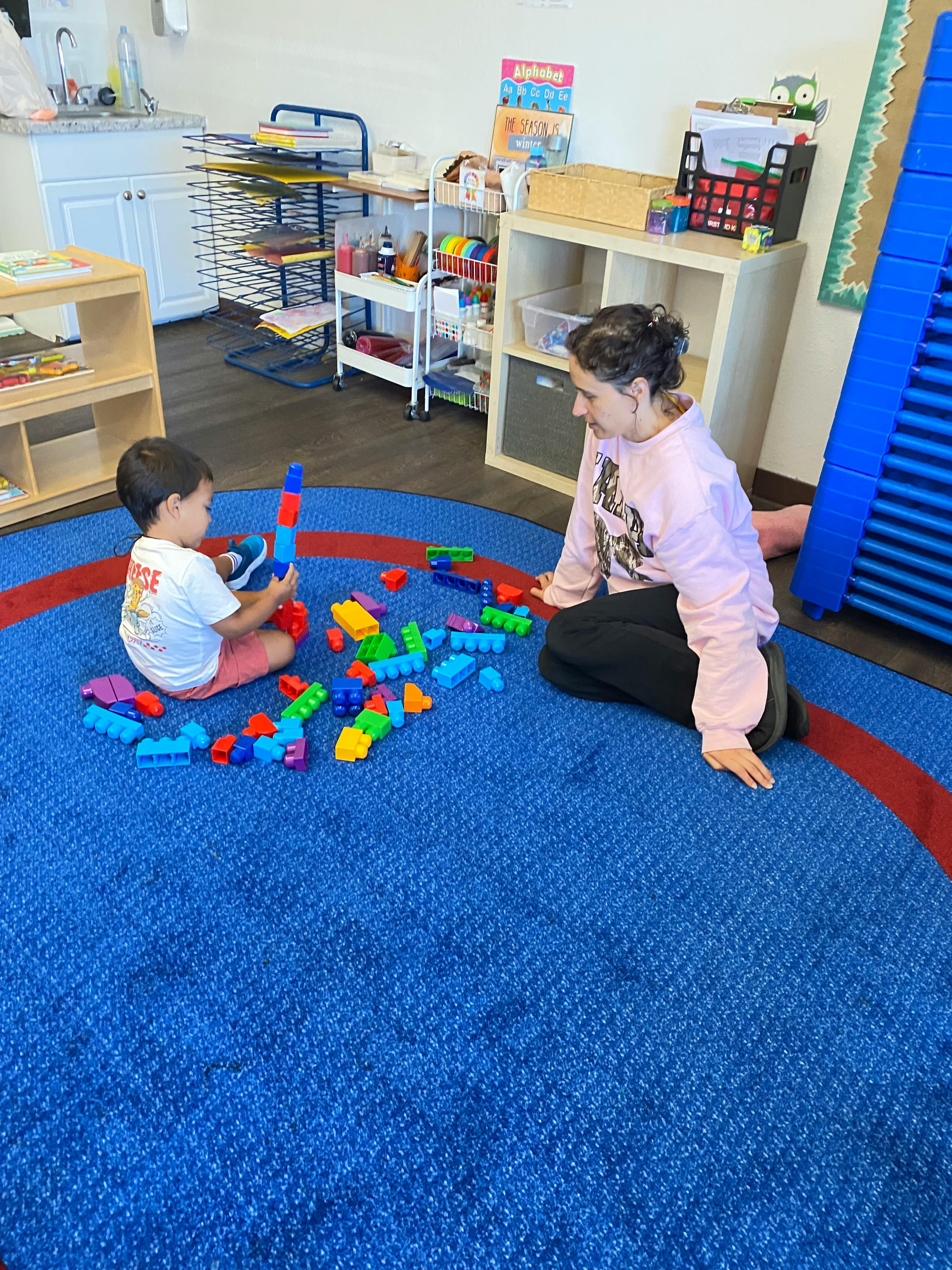 Adult and child playing with colorful building blocks on a blue rug
