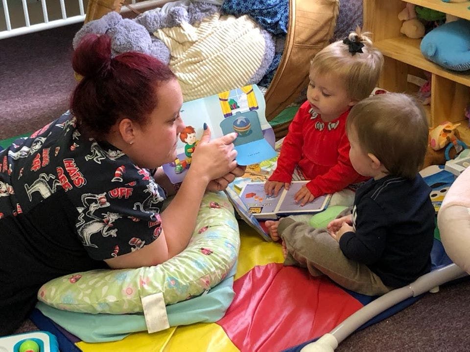 Person reading a book to two children