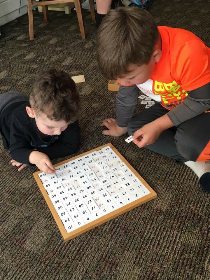 Two children on the floor playing with a number board